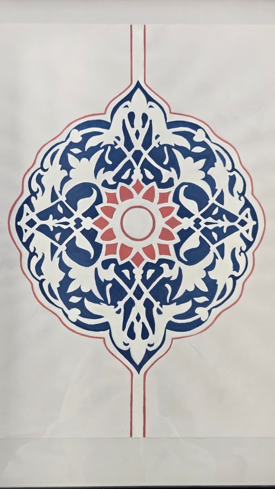 A lobed medallion painted in deep indigo on cream paper, its interior cut through with pale split-leaf scrolls around a coral twelve-petal flower, a thin coral line running through the centre from top to bottom