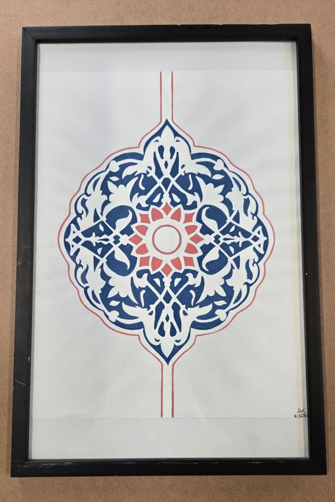 The same indigo and coral rosette signed and set behind glass in a slim black frame